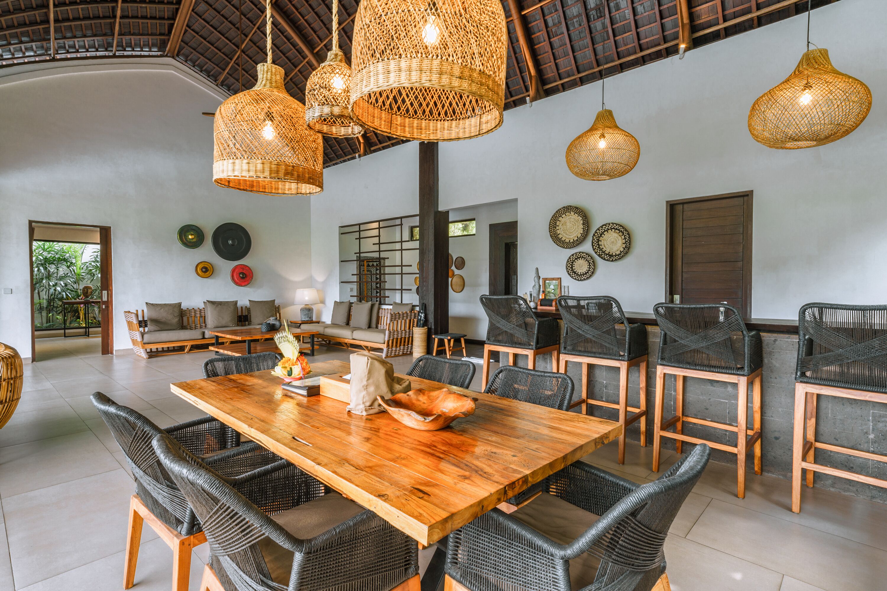 A spacious dining area with a wooden table and wicker chairs, surrounded by large woven pendant lights.