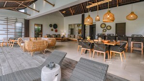 A spacious dining area with wicker furniture, hanging wicker light fixtures, and a high ceiling with exposed beams. - KClub Ubud (Tegallalang)