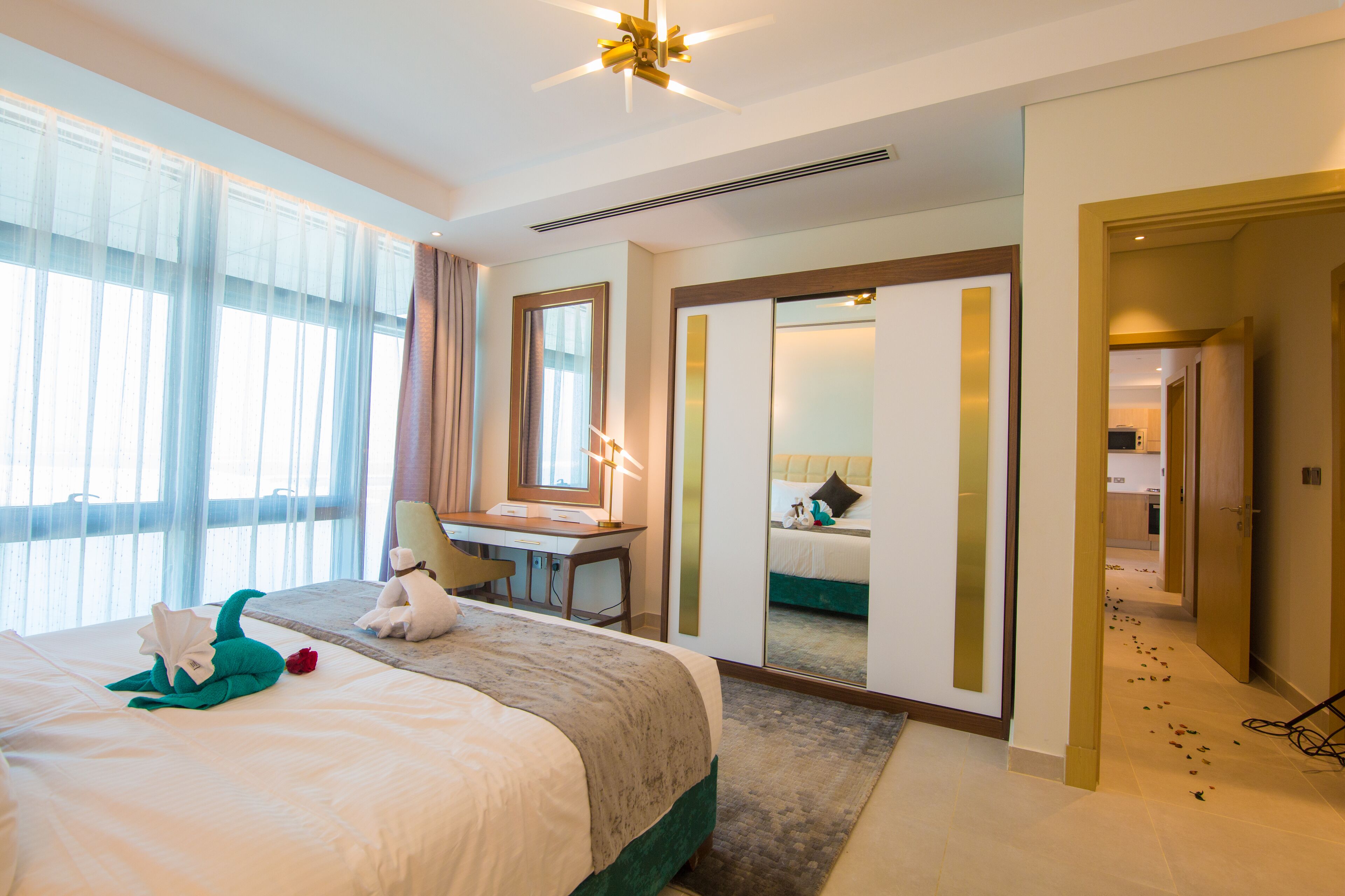 A hotel room with a large bed, a desk, a mirror, and a view of the bathroom.