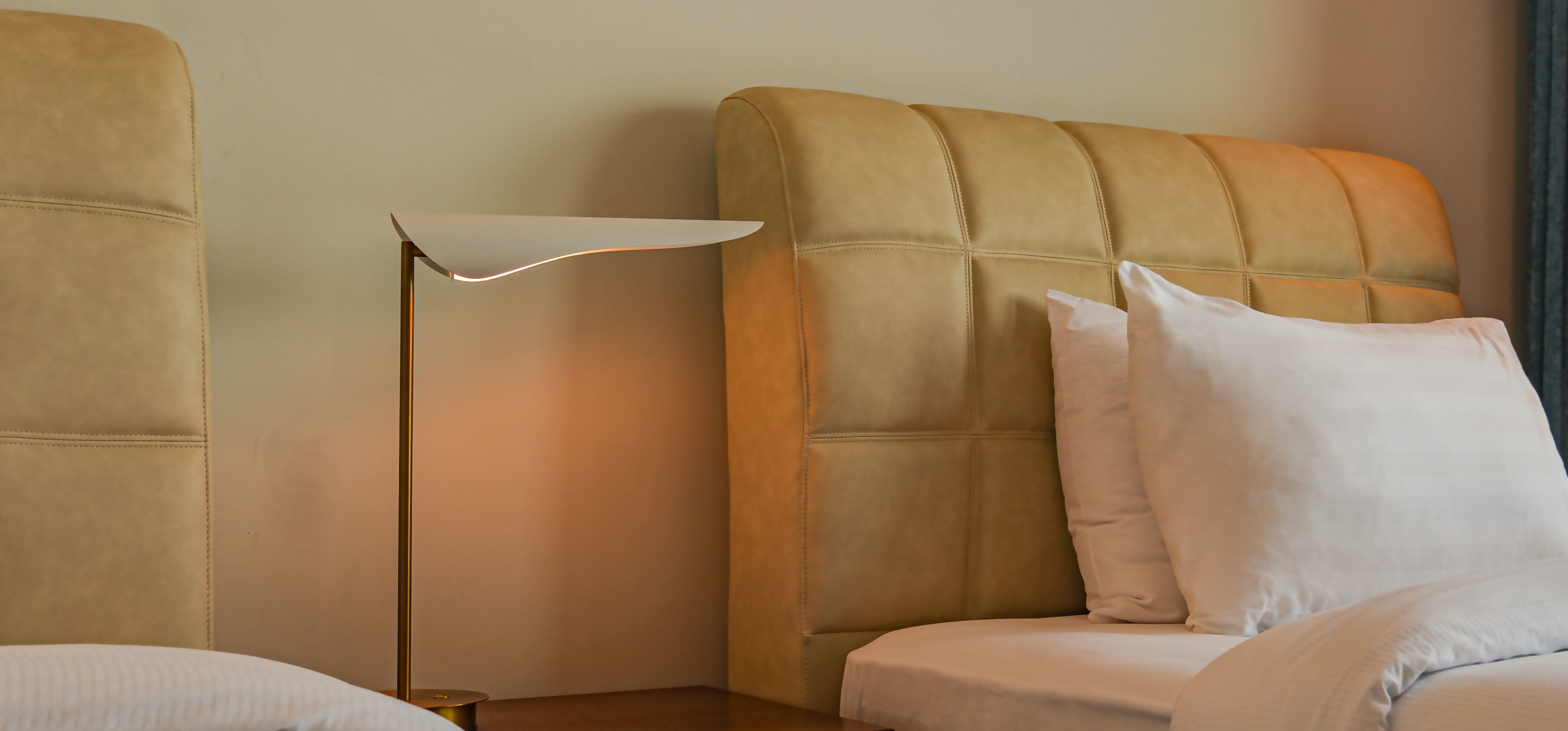 A hotel room with a large bed, a bedside lamp, and a headboard.