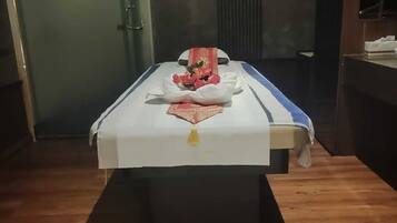 Experience a serene massage in a tranquil space with a massage table, candle, and bathroom access.