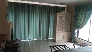 Une pièce comprenant un lit, une chaise, une armoire et une fenêtre avec des rideaux.