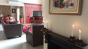 Un salon avec une cheminée, un téléviseur et un coin repas agrémenté d’un rideau rouge.