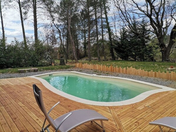 A wooden deck with a swimming pool, surrounded by a wooden fence and trees.