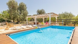 A rectangular swimming pool with a wooden deck, surrounded by lounge chairs and a pergola. - Trullo Aia Antica - Ceglie Messa... (Ceglie Messapica)