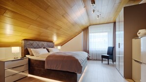 Een slaapkamer met een houten plafond, een bed met hoofdeinde, een nachtkastje, een stoel en een kledingkast.