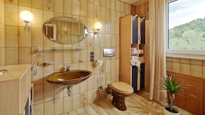Een badkamer met een houten wastafelmeubel, een wastafel, toilet, spiegel en een raam met uitzicht op een groen landschap.