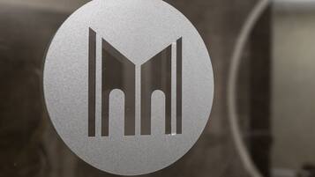 Un logo circulaire représentant la silhouette stylisée d’un bâtiment.