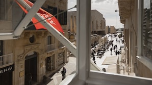Vista de una calle con un edificio que tiene un gran letrero rojo de Coca-Cola, una acera para peatones y una mezcla de estilos arquitectónicos.
