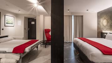 Habitación de hotel con dos camas, una silla roja, un espejo grande y una lámpara moderna.