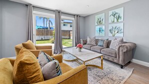 Ein Wohnzimmer mit einer Couch, Sesseln, einem Couchtisch und Kunstwerken an der Wand.