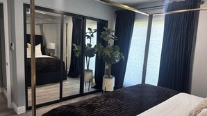 Ein modernes Schlafzimmer mit einem großen Bett, einem Spiegel und Blick auf einen Balkon.