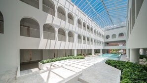 Et moderne atrium med en central swimmingpool, hvide vægge og buede vinduer.