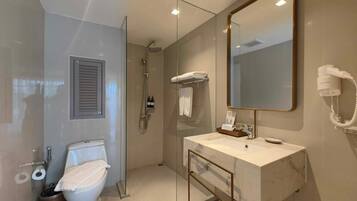 A modern bathroom with a glass-enclosed shower, a white toilet, a marble sink, and a large mirror.
