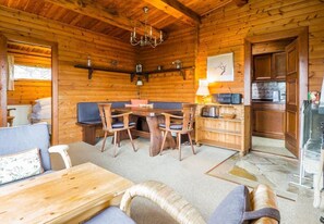 Cozy cabin-style interior with a dining table, sofa, and kitchen area.