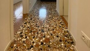 A hallway with a terrazzo floor leading to a living area with a sofa. - Ca' Berto Apartment (Venezia)