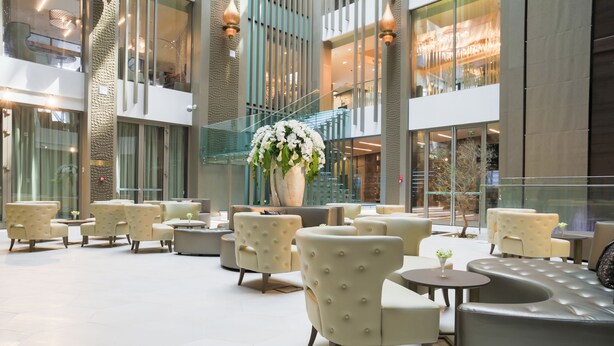A spacious indoor area with multiple seating arrangements, including sofas and chairs, and a large decorative vase with flowers. - The Legacy Luxury hotel Algiers Hydra (Algiers)
