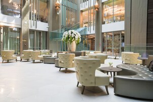 A spacious indoor area with multiple seating arrangements, including sofas and chairs, and a large decorative vase with flowers.