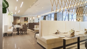 A modern restaurant with white booths, tables with set dining ware, and a ceiling with linear lighting. - The Legacy Luxury hotel Algiers Hydra (Algiers)