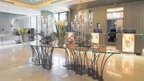 A modern hotel lobby with a glass-top reception desk, decorative vases, and a chandelier. - The Legacy Luxury hotel Algiers Hydra (Algiers)