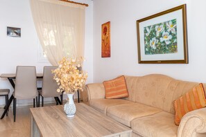 A living room with a sofa, a coffee table, and a dining area with chairs and a table.