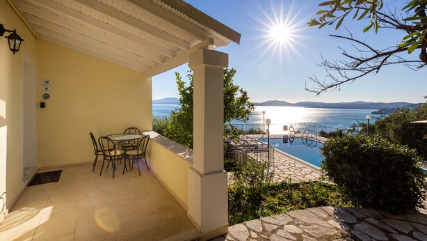 A covered outdoor area with a pool, a table with chairs, and a view of the sea. - Villa Katina - private pool & sea view (Corfu)