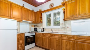 A kitchen with wooden cabinets, a white refrigerator, a stove, and a microwave. - Villa Katina - private pool & sea view (Corfu)
