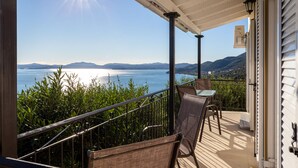 A balcony with a view of the sea and mountains, a table, and two chairs. - Villa Katina - private pool & sea view (Corfu)