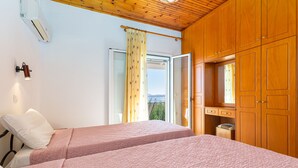 A bedroom with two beds, wooden cabinets, a ceiling fan, and a window with curtains. - Villa Katina - private pool & sea view (Corfu)