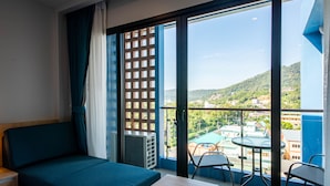 Habitación de hotel con balcón, sofá, mesa y sillas.