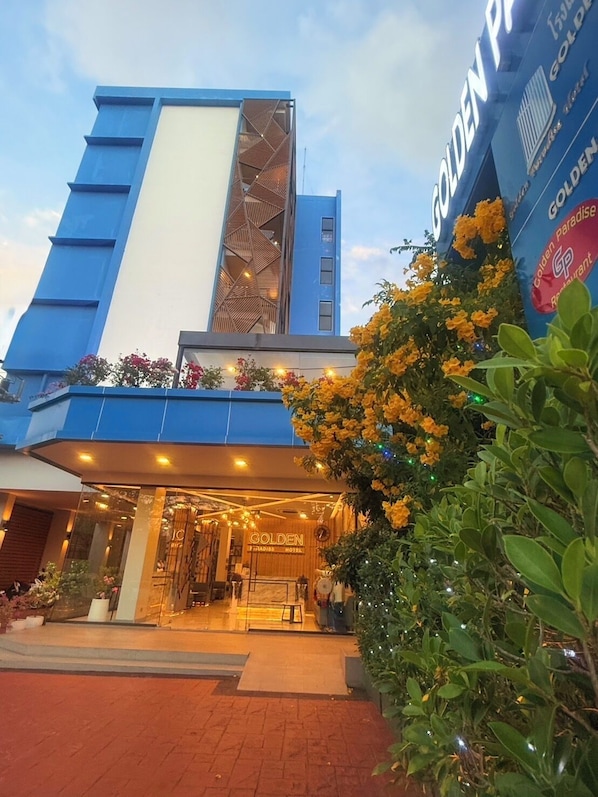 A hotel with a prominent blue facade, a visible entrance, and a sign indicating it is the Golden Paradise Hotel.