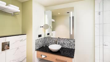 Un baño moderno con lavamanos blanco, encimera negra y espejo arriba.