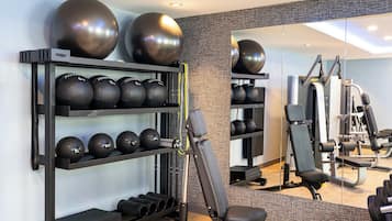 A gym with exercise equipment, including a bench press, a squat rack, and various weights.