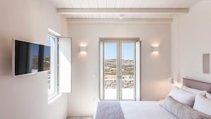 Camera da letto con un letto, una TV, una porta scorrevole in vetro che dà su un balcone e vista su un paesaggio roccioso.