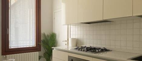 A compact kitchen with a gas stove, oven, and white cabinets.
