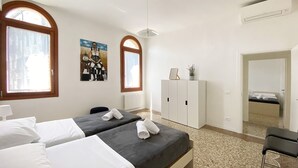 Une chambre d’hôtel avec deux lits, un radiateur, une plante en pot et un tableau au mur.