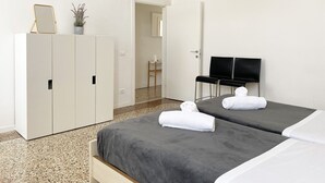 Une chambre d’hôtel avec un lit, deux tables de chevet, une armoire, un téléviseur et une plante en pot.