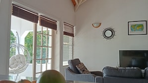 A living room with a wooden ceiling, a television, a sofa, and a fruit basket.
