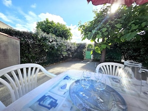 Eine Terrasse im Freien mit einem Tisch für zwei Personen, zwei Weingläsern und einer Karaffe.