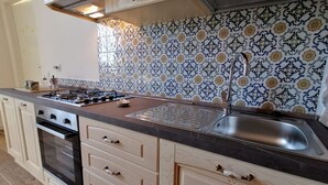 Cocina con estufa a gas, horno, pileta y salpicadero con diseño.