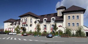 A hotel with a traditional architectural style, featuring multiple stories, arched windows, and a central entrance. - Hotel Hanul Domnesc (Sacele)