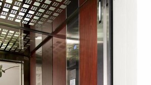 Un ascenseur doté d’un panneau en bois et de portes en acier inoxydable.