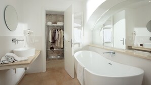 Een moderne badkamer met een vrijstaand bad, een grote spiegel en een wastafelmeubel met een wastafel.