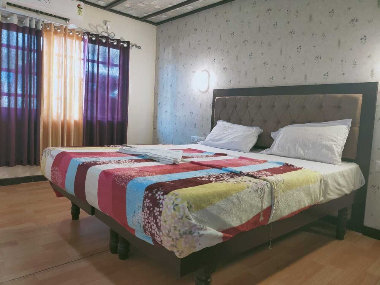 Una cama con una colcha de estampado floral, un cabecero y almohadas blancas.