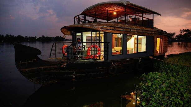 A houseboat with a covered deck, windows, and a lifebuoy. - Private Houseboat (Ambalapuzha)