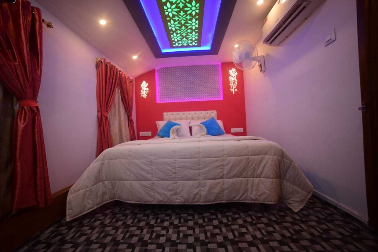 A bedroom with a bed, red curtains, a patterned floor, and a ceiling light fixture.