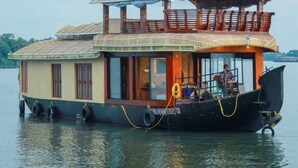 A houseboat with a covered upper deck, windows, and a black hull. - Private Houseboat (Ambalapuzha)