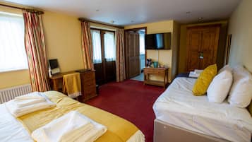 Una habitación de hotel con dos camas, un escritorio, un televisor y un armario.
