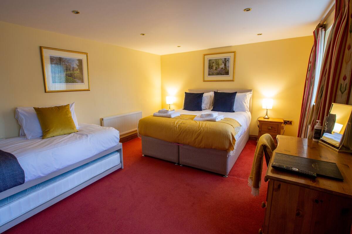 A hotel room with two beds, a wooden desk, and a mirror.