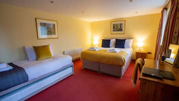 A hotel room with two beds, a wooden desk, and a mirror.